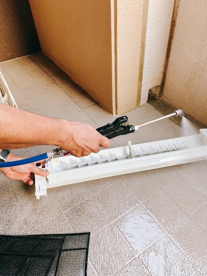 エアコンのドレンパン（排水受け皿）を水洗い清掃している様子