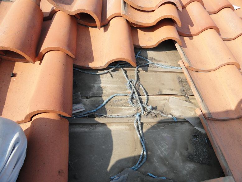 屋根内部の防水紙が破れ、下地の野地板が露出している状態。雨水のしみも確認できる